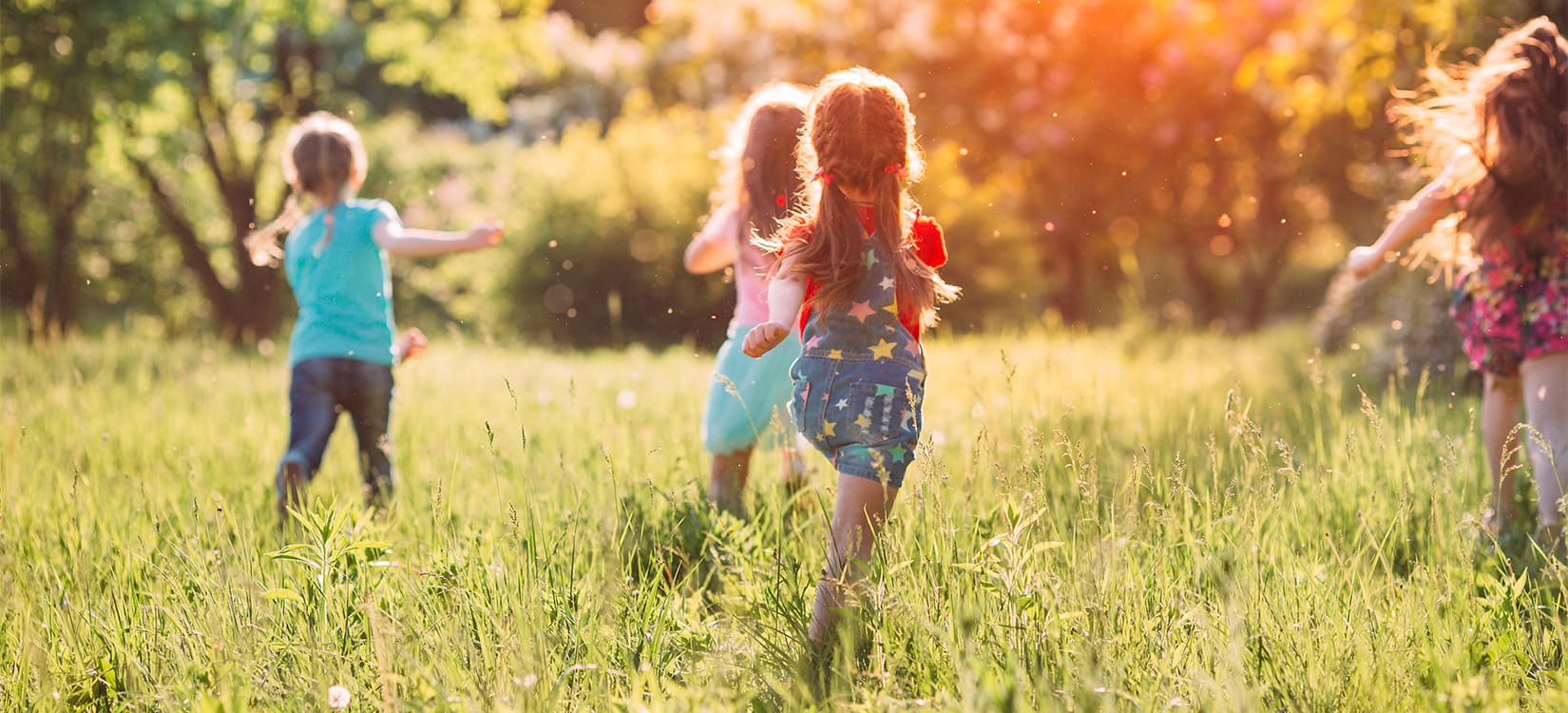 Kleine Mädchen laufen auf der Wiese im Sonnenschein