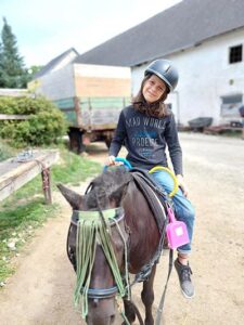 Beim Reitcamp. Kind sitzt auf Pferd und lächelt.