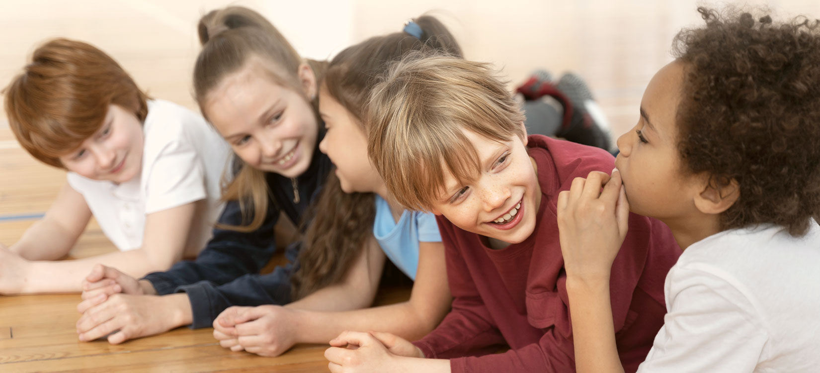 Fröhliche Kinder liegen am Boden und lächeln